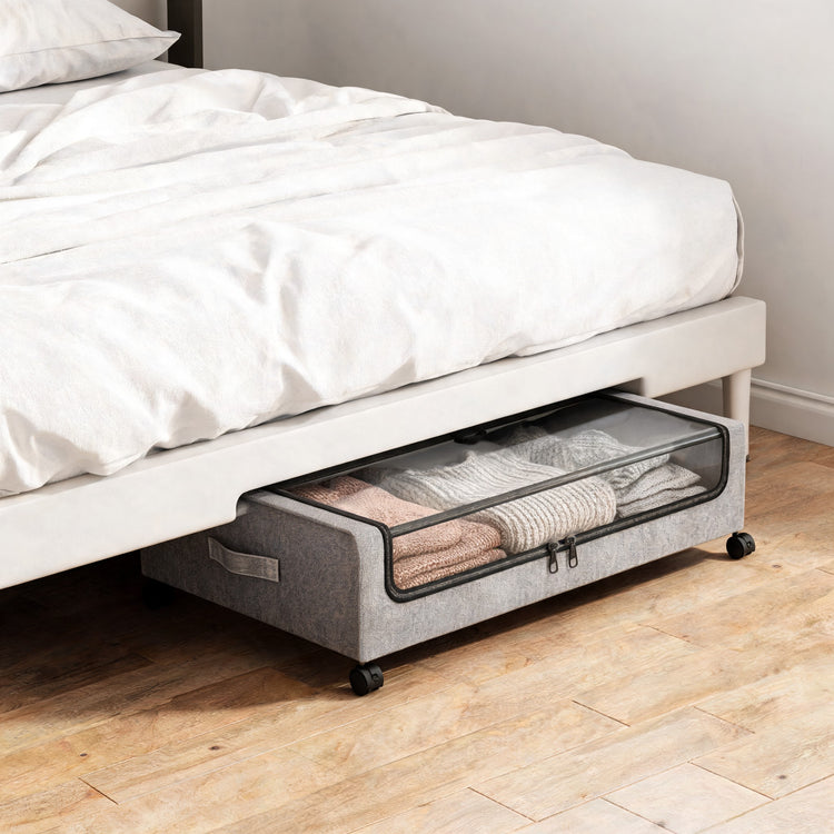Rolling underbed storage container with clear lid pulled out from under a bed