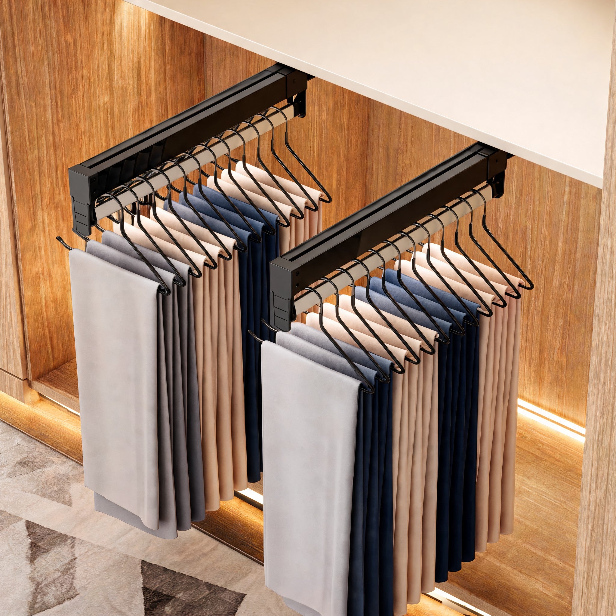 Two black pull-out trouser racks holding pants in a lit wardrobe