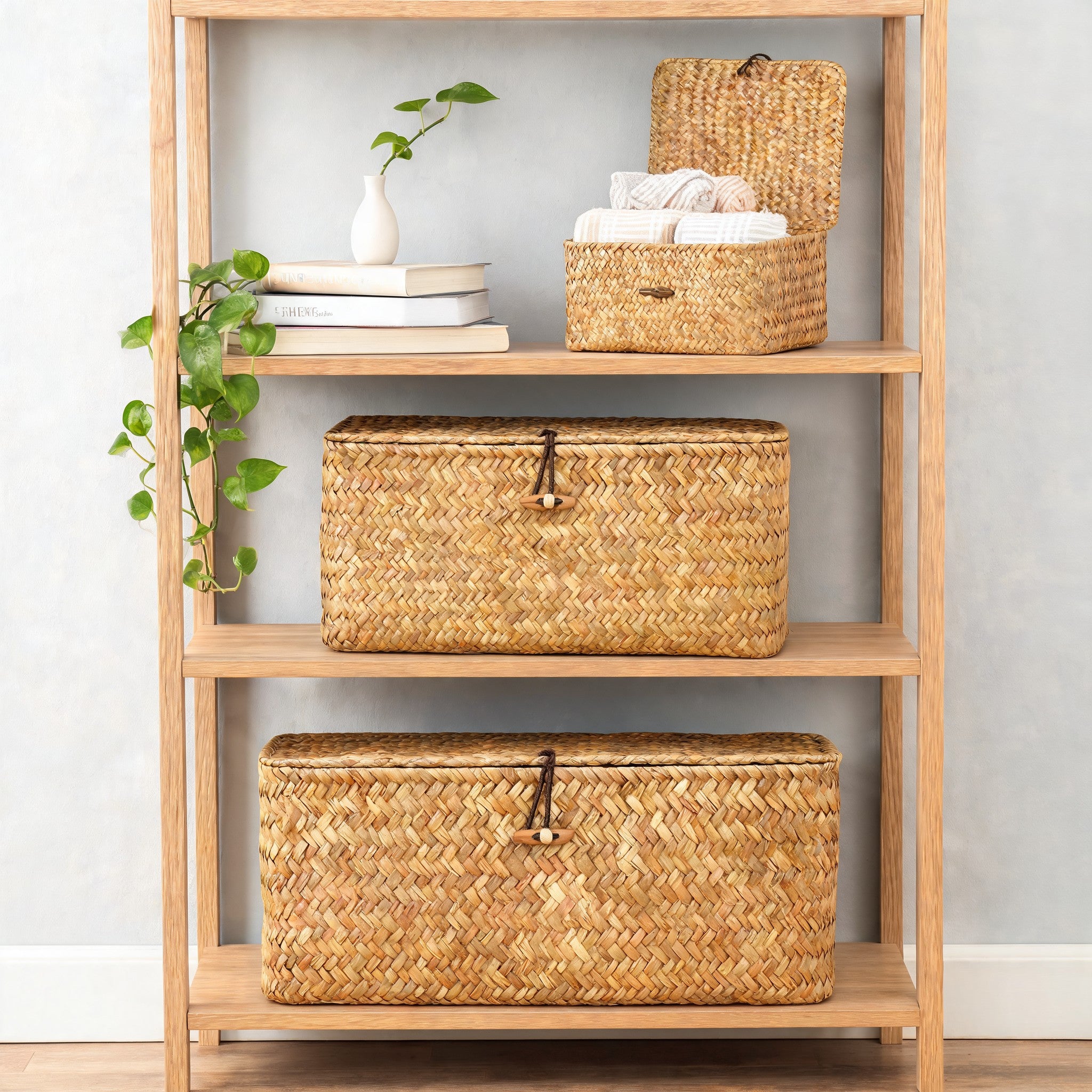 Three seagrass storage baskets with lids on oak shelving