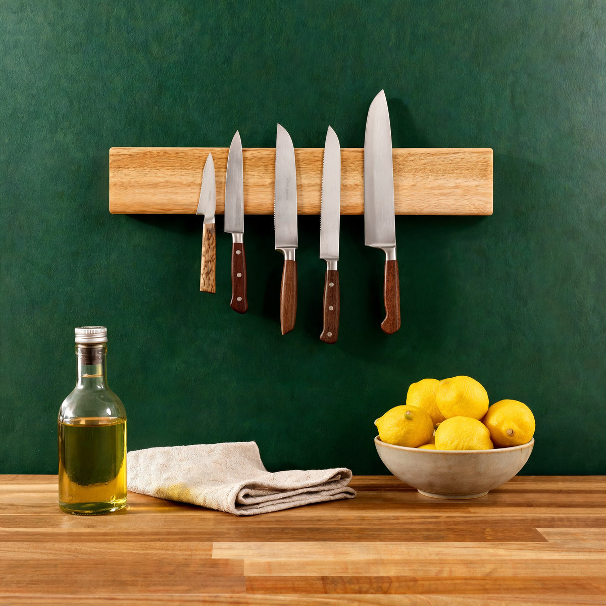 Acacia knife strip with knives on a dark green kitchen wall